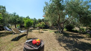 A barbecue grill with vegetables, a hammock, and a chair in a sunny outdoor area with trees. - Apartment 'Vanedda Di Mari - Casa Arancio' with Shared Terrace, Wi-Fi & Air Conditioning (Messina)
