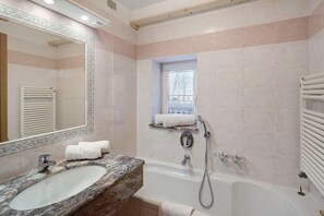Ein Badezimmer mit Marmorwaschbecken, einer Badewanne, einem Handtuchhalter und einem Fenster mit Blick.