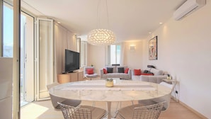 A modern living room with a marble dining table, wireframe chairs, a large TV, and a chandelier. - Stunning Apartment a/c 6P With Sea View - Cannes (Cannes)