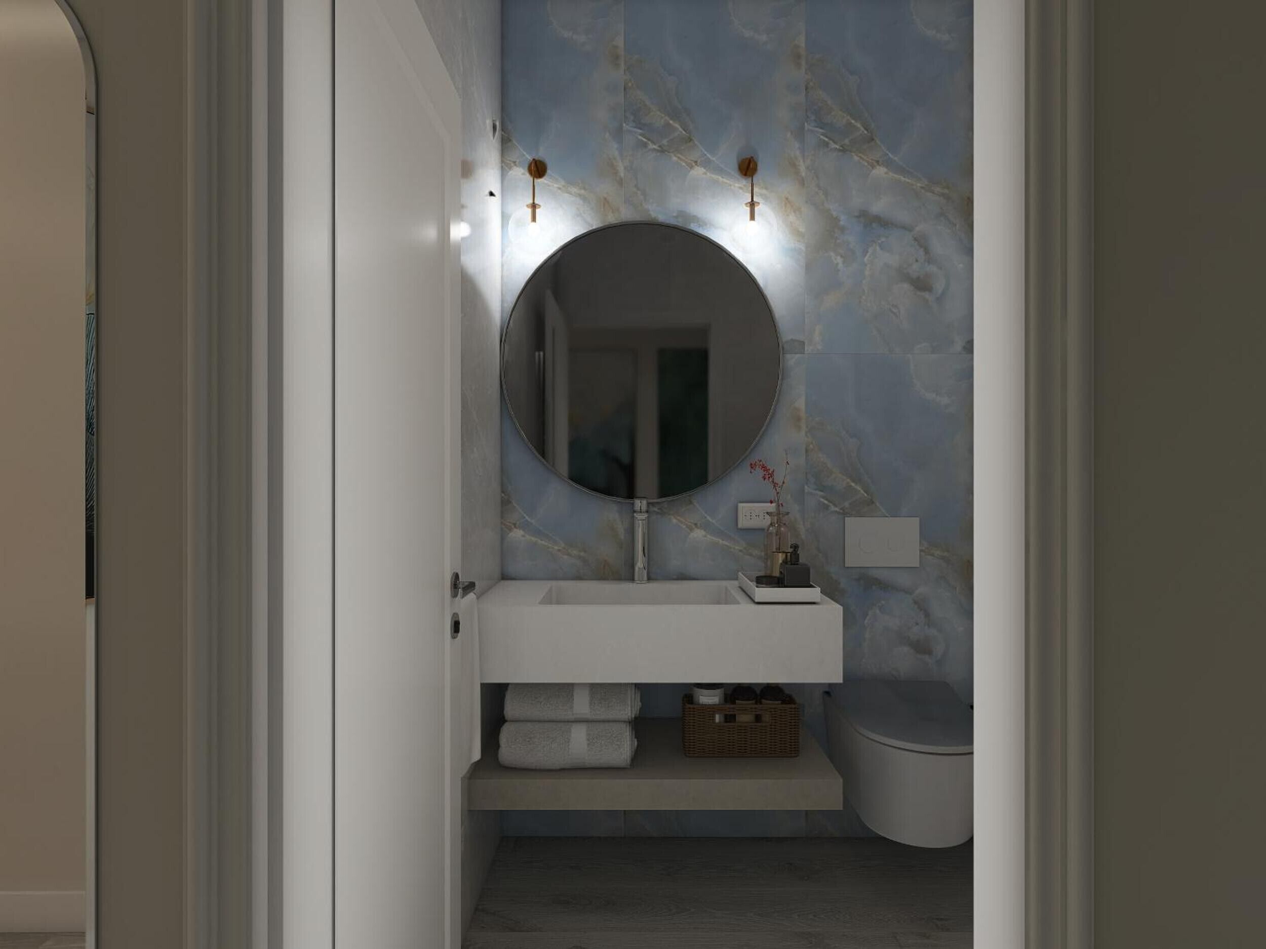 A bathroom with a marble wall, a round mirror, a white sink, and a toilet.