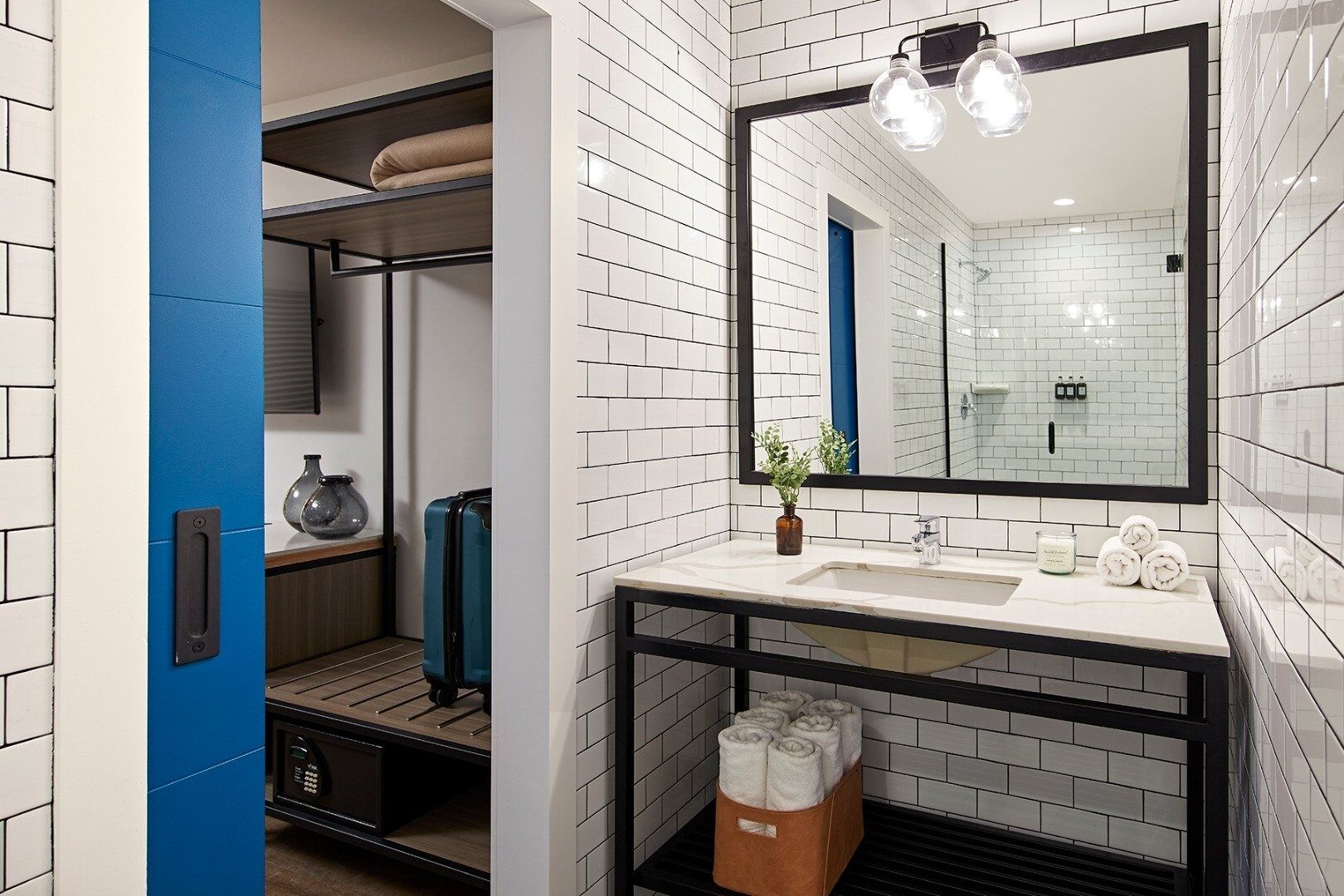 A modern bathroom with white subway tiles, a large mirror, and a blue accent wall.