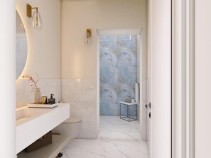 Ein modernes Badezimmer mit einem weißen Waschtisch, einer Glasdusche und Marmorböden.