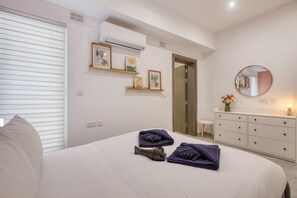 Ein Schlafzimmer mit Bett, Kommode, Spiegel und Tür.