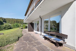Ein Gebäude mit Balkon, Steinweg und Bänken.