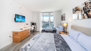 Hotellihuone, jossa on sänky, työpöytä, televisio, ikkuna, josta avautuu näkymä kaupunkiin, sekä taideteoksia seinillä.