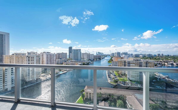 Een rivier met gebouwen aan beide oevers, een heldere lucht en een balkon met een hekwerk.