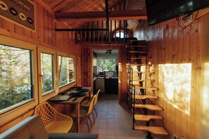 A wooden interior with a dining area, kitchen, and a staircase.