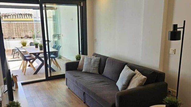 Een moderne woonkamer met een bank, een rond bijzettafeltje en een eethoek met stoelen en een tafel.