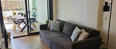 Ein modernes Wohnzimmer mit einer Couch, einem runden Beistelltisch und einem Essbereich mit Stühlen und Tisch.