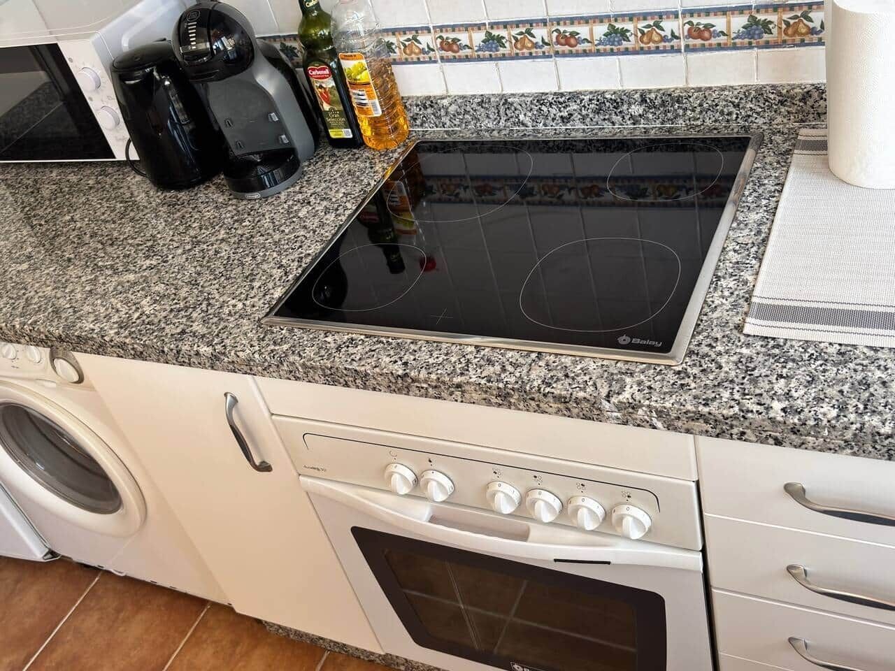 A kitchen with a stove, oven, washing machine, and a coffee maker.