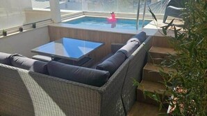 Un balcone con un divano in vimini, un tavolino in vetro e vista sul mare.
