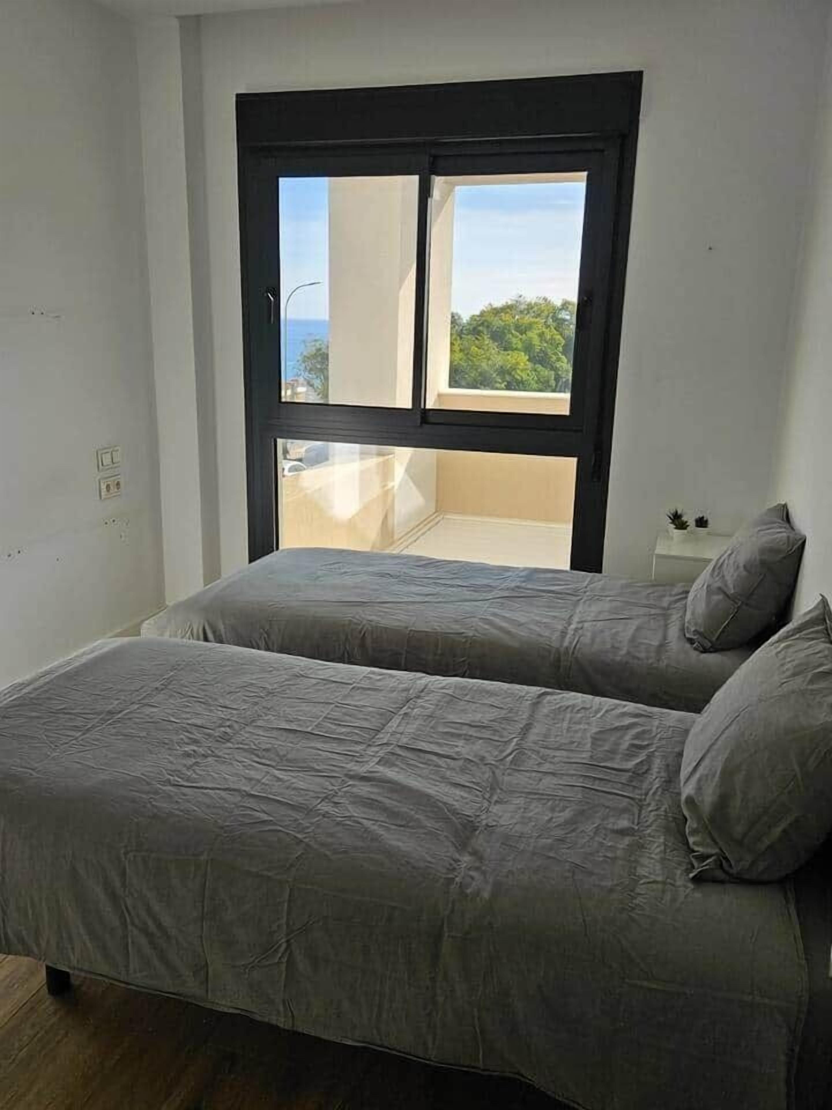 Une chambre avec deux lits, une fenêtre et une petite table sur laquelle est posée une plante.