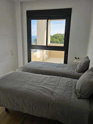 A room with two beds, a window, and a small table with a plant. - Horizon Del Mar – Sea Views & Plunge Pool – 2BR, 2BA, Sleeps (Torremolinos)