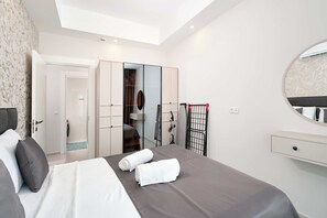 Una habitación de hotel moderna con una cama, un armario, un espejo y un pequeño escritorio.