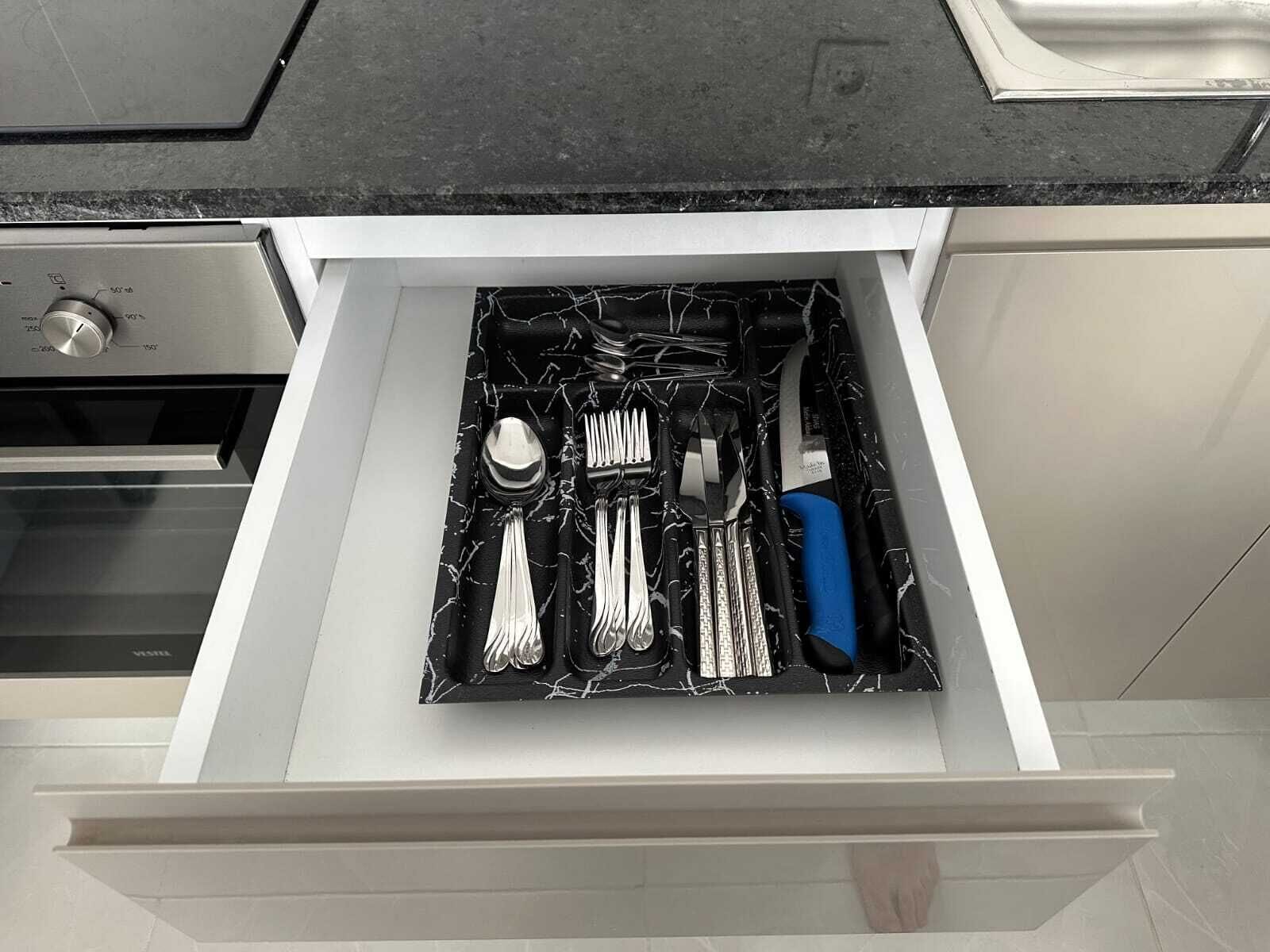 A kitchen drawer with utensils and a blue-handled knife.