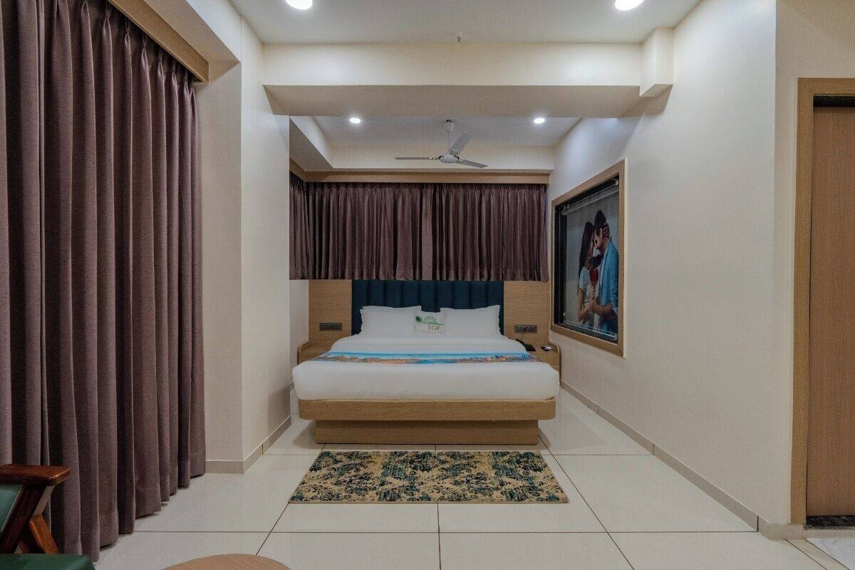 Un dormitorio con cama, cortinas, ventilador de techo, un cuadro y una mesita de noche.