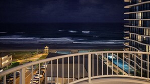 A high-rise building with a balcony overlooking a beach and ocean. - Spacious Ocean View Unit — Pool, Tennis & Beaches (Surfers Paradise)