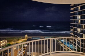 Un immeuble de grande hauteur doté d’un balcon donnant sur une plage et l’océan.