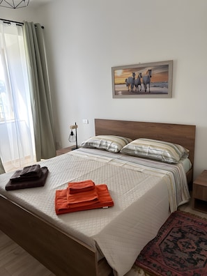 Una cama bien hecha con almohadas, una manta doblada y una toalla doblada sobre la cama.