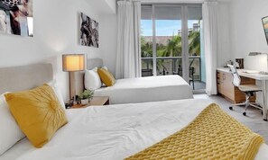 A modern hotel room with a bed, desk, and large window. - Intracoastal Retreat -2BR (Hallandale Beach)
