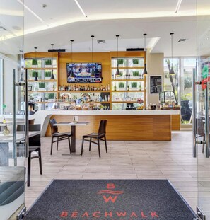 A modern bar area with a TV screen, wooden counter, and seating. - Intracoastal Retreat -2BR (Hallandale Beach)