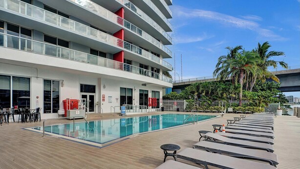 Un hôtel doté d’une piscine, de chaises longues et offrant une vue sur les palmiers.