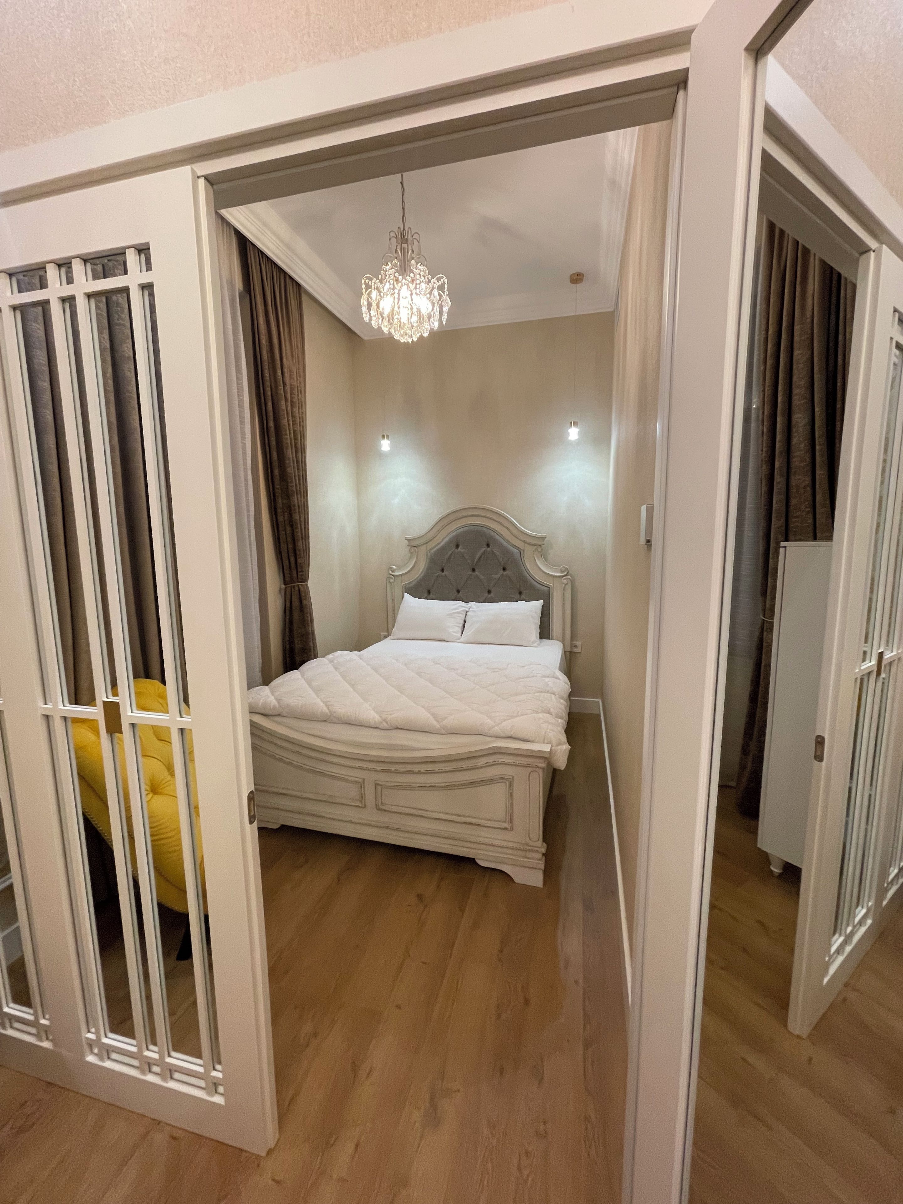 Une chambre à coucher avec un lit, un lustre et une armoire.