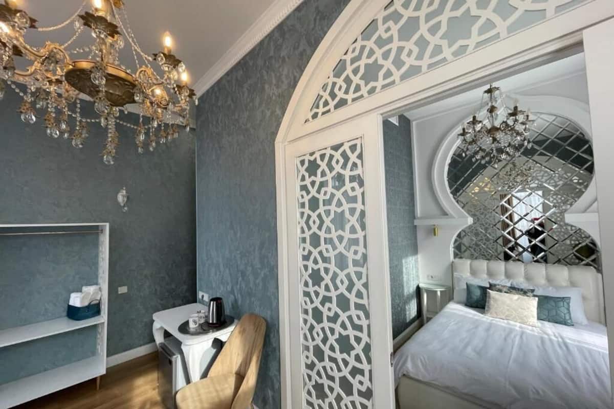 Ein Schlafzimmer mit Bett, Stuhl, Schreibtisch, einer Kandelaber und dekorativen Wandverkleidungen.