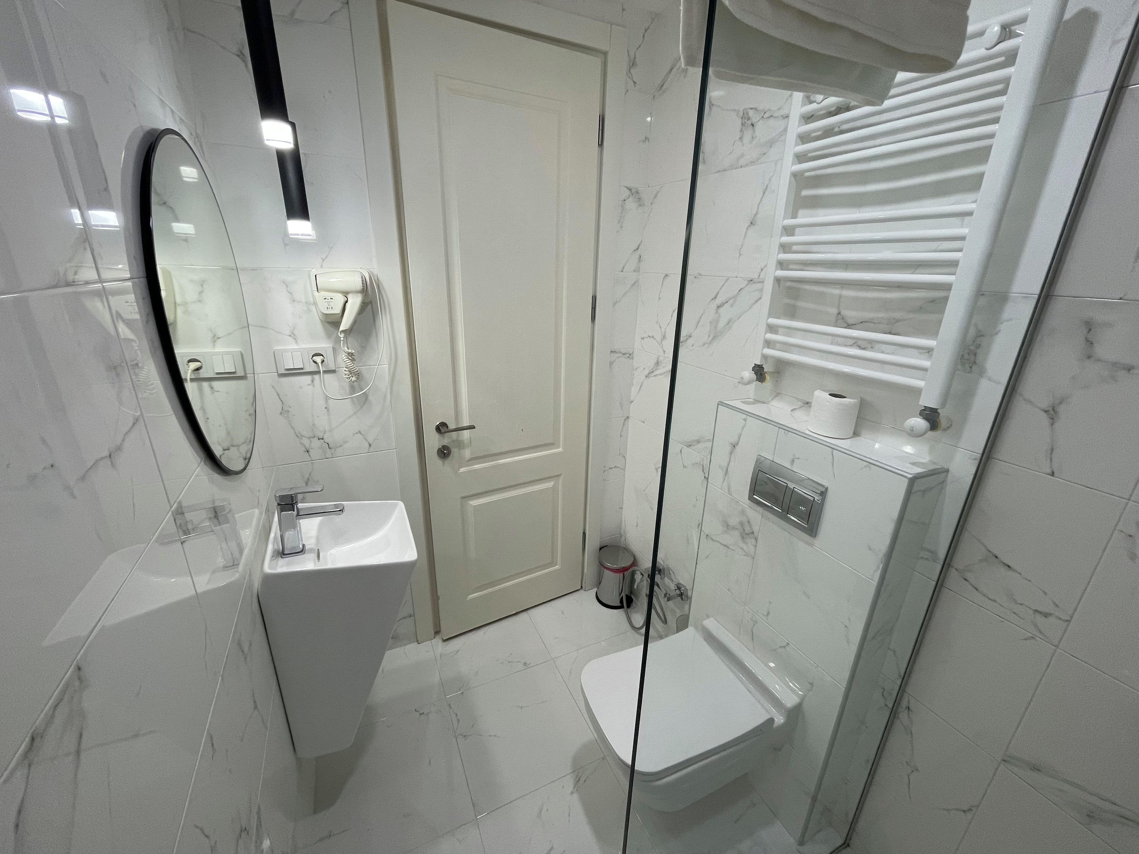 Een moderne badkamer met een wit wastafel, toilet en douche.
