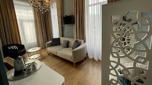 Una sala de estar moderna con un sofá, una mesa de centro, una araña y un televisor montado en la pared.