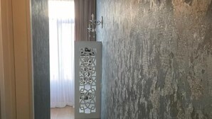 Un pasillo estrecho con paredes texturizadas, un armario blanco con paneles decorativos y una lámpara en el techo.