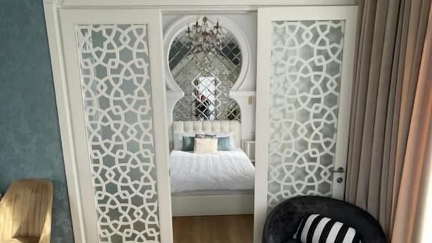 Un dormitorio con una cama, una silla, un sofá y un arco decorativo.