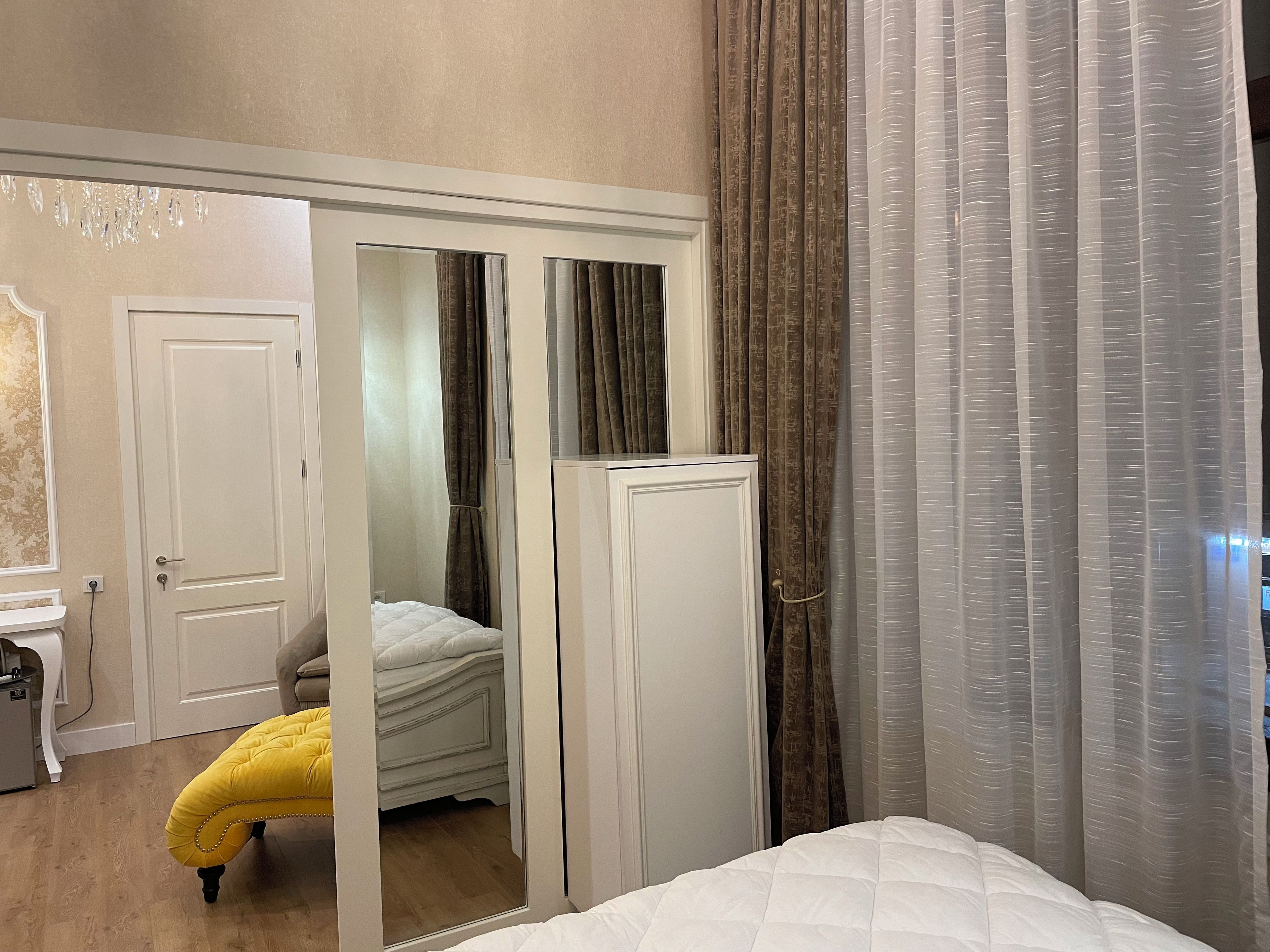 Ein Schlafzimmer mit Bett, Schrank, Spiegel und einer Tür zu einem anderen Raum.