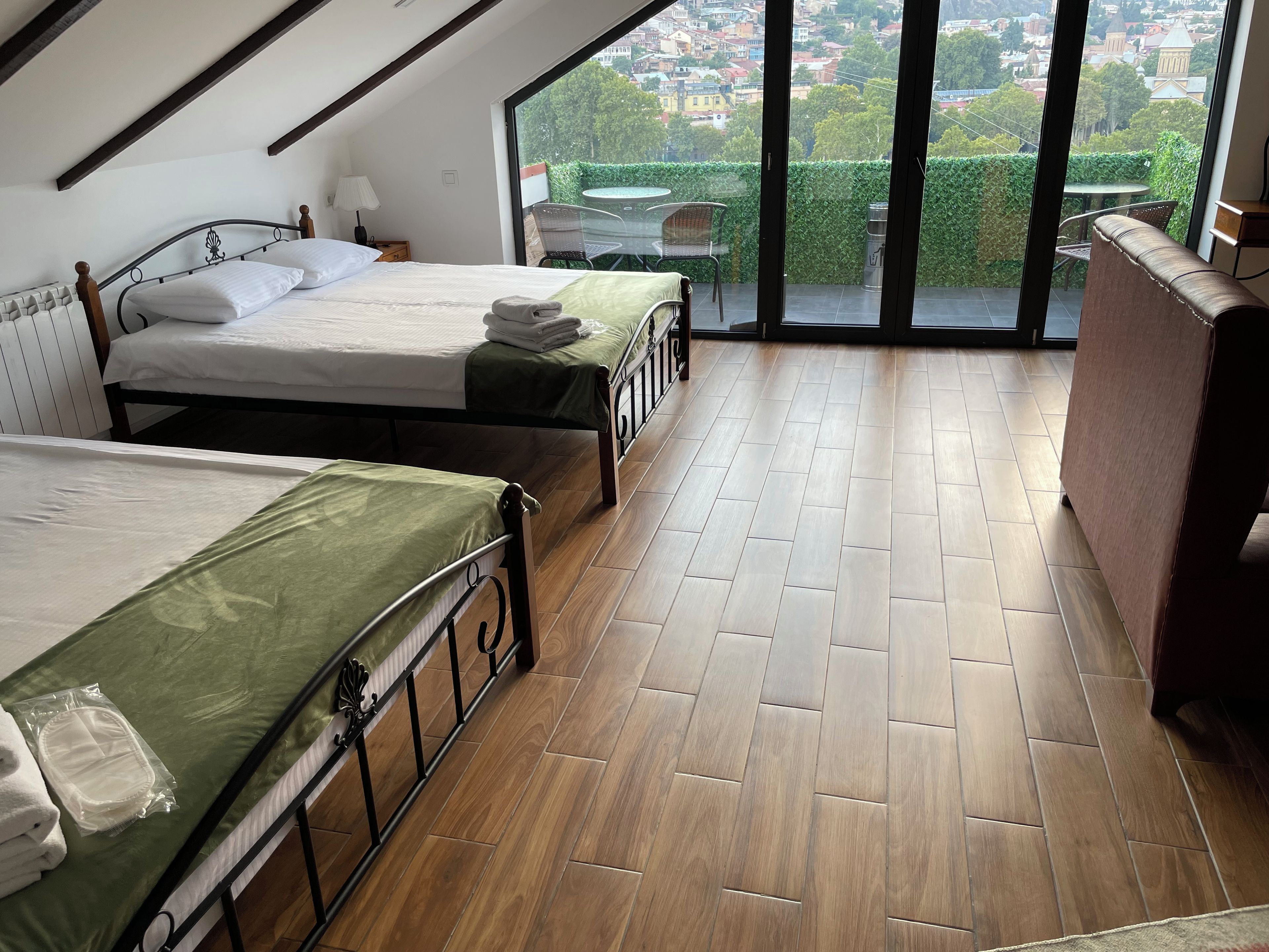 Une chambre avec deux lits, un balcon et une vue sur la ville.
