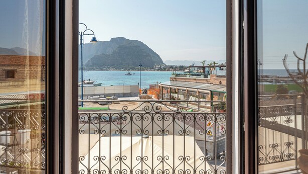 Ein Balkon mit Blick auf eine Küstenlandschaft, inklusive Berg, Wasser und Gebäuden.