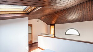 Ein Zimmer mit schrägverdeckter Decke, Oberlicht und einer festen Sitzbank an der Wand.