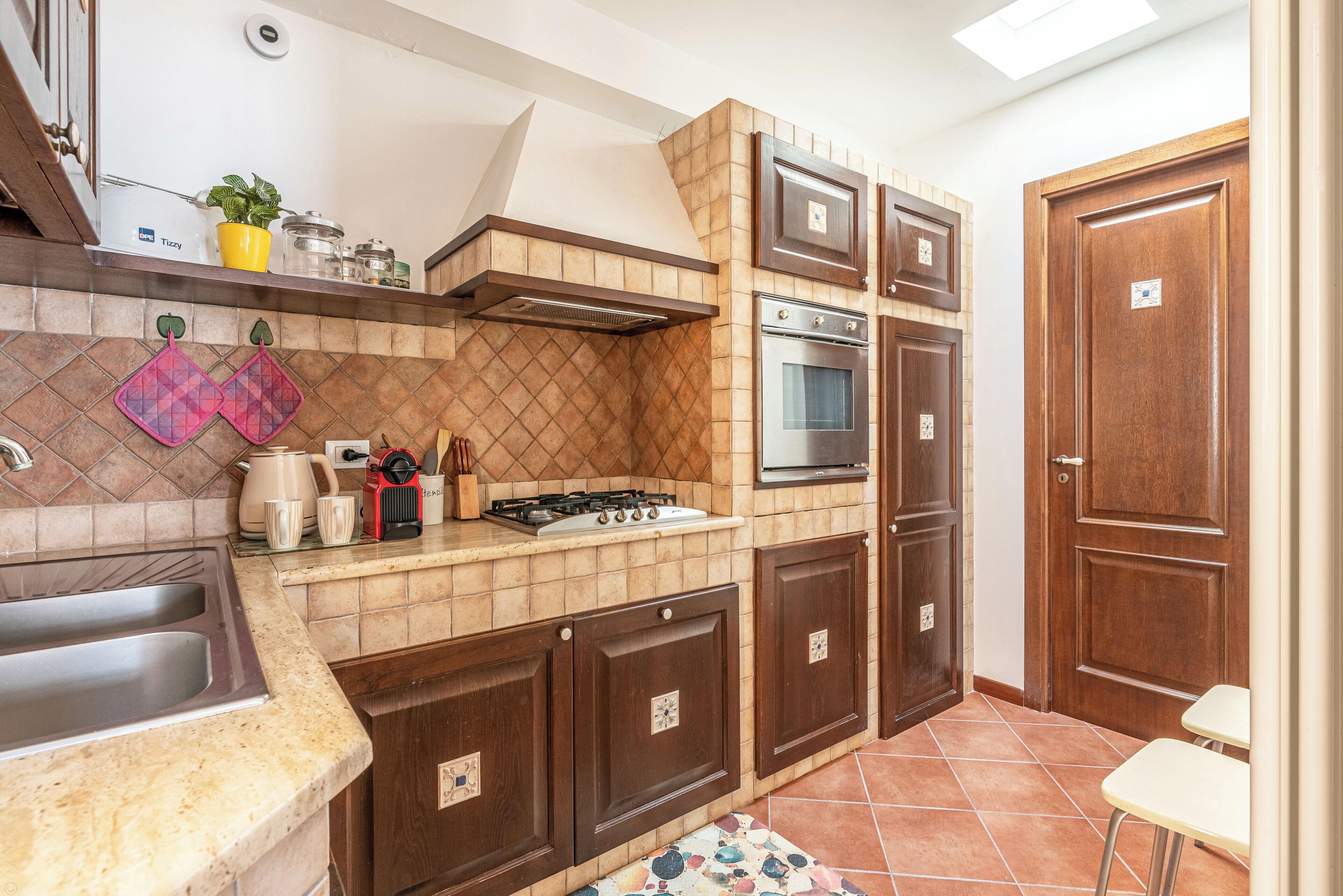 A kitchen with a gas stove, oven, and a sink. There are cabinets and a countertop.