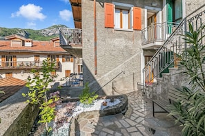 Un patio con un banco de piedra, un jardín pequeño y una escalera que conduce a un piso superior.