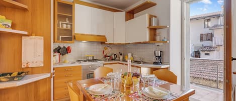 Eine moderne Küche mit Holzausstattung, einem Esstisch für vier Personen und Blick ins Freie.