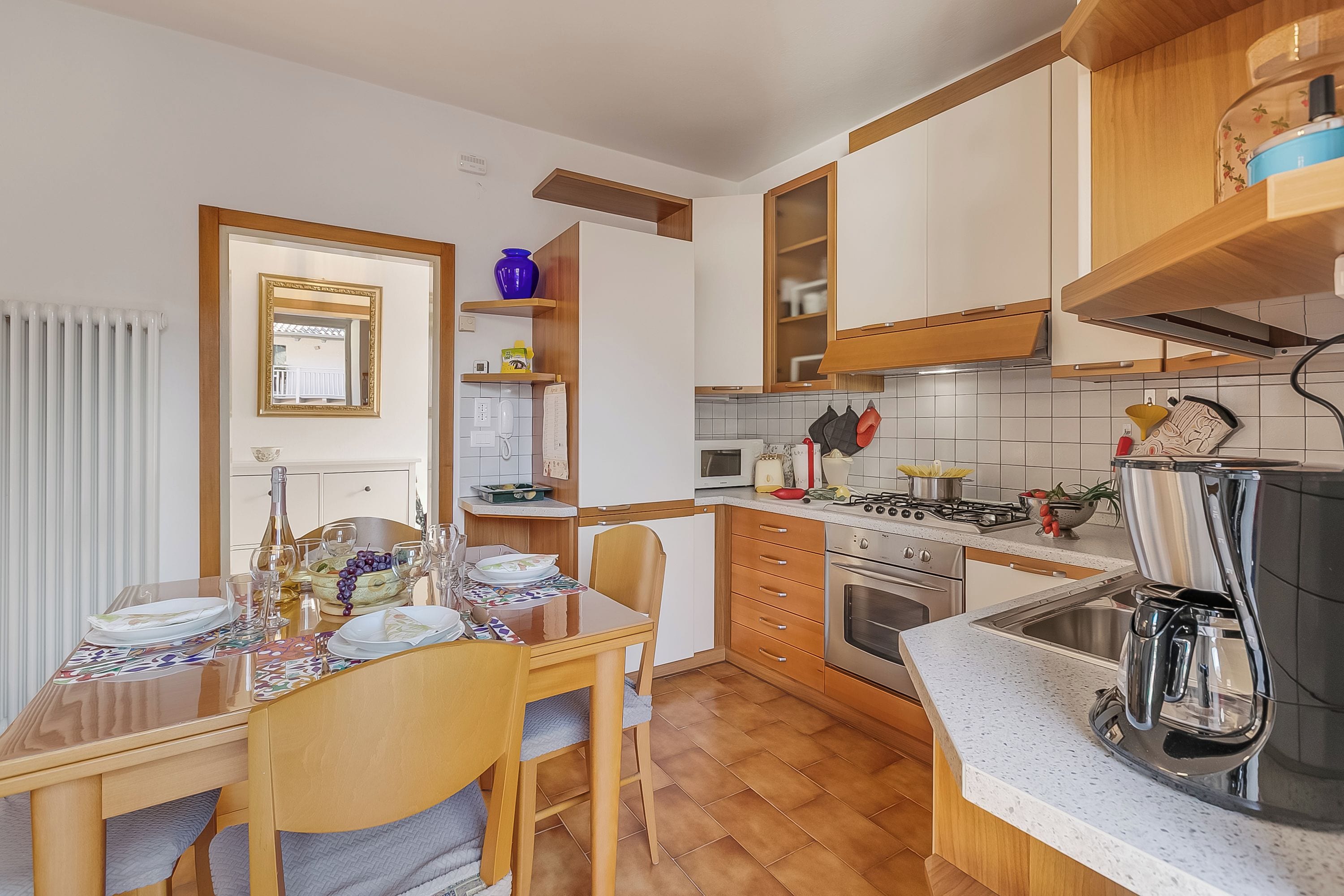 Una cocina con armarios de madera, una mesa de comedor para cuatro personas y una cafetera.
