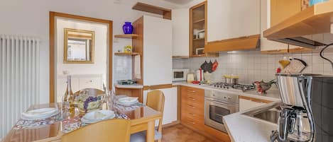 Una cocina con armarios de madera, una mesa de comedor para cuatro personas y una cafetera.