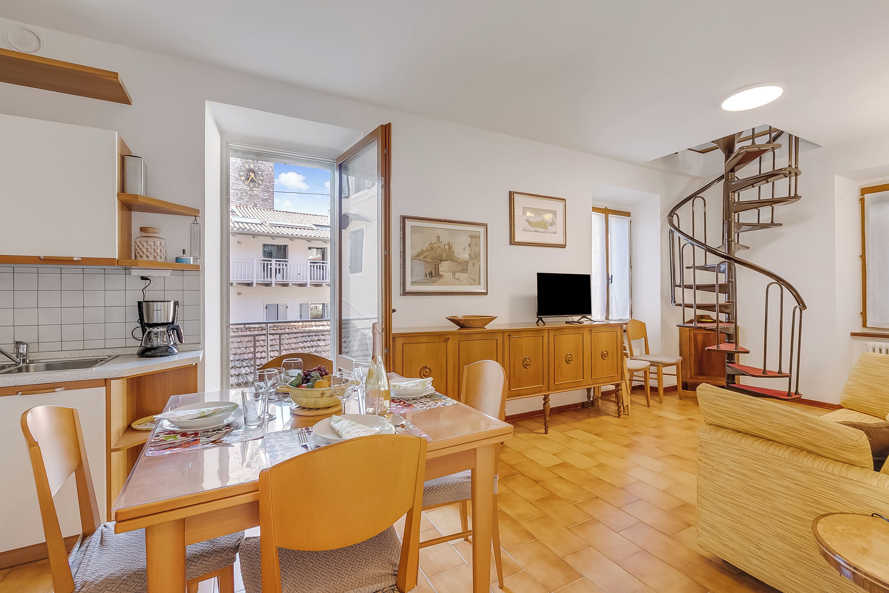 Une cuisine moderne avec un coin repas, un téléviseur et un escalier en colimaçon.