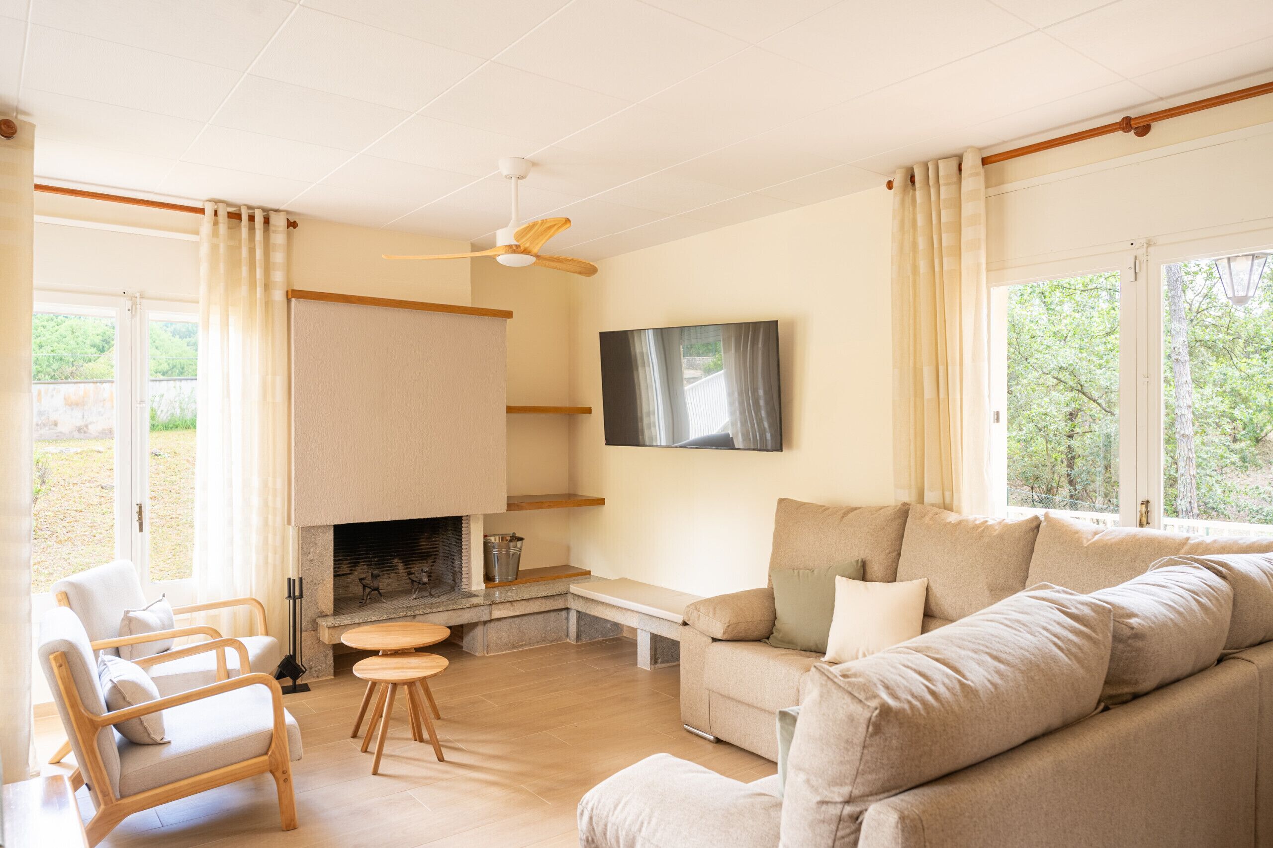 Un salon comprenant un canapé, des fauteuils, une cheminée, un téléviseur et un ventilateur de plafond.