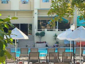 A poolside area with lounge chairs and umbrellas, a staircase leading to a balcony, and a building with large windows and a balcony. - SIRIUS HOTEL (Kemer)