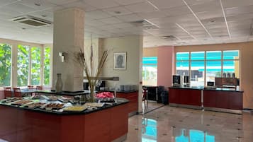 A hotel lobby with a central island counter, large windows, and a tiled floor.