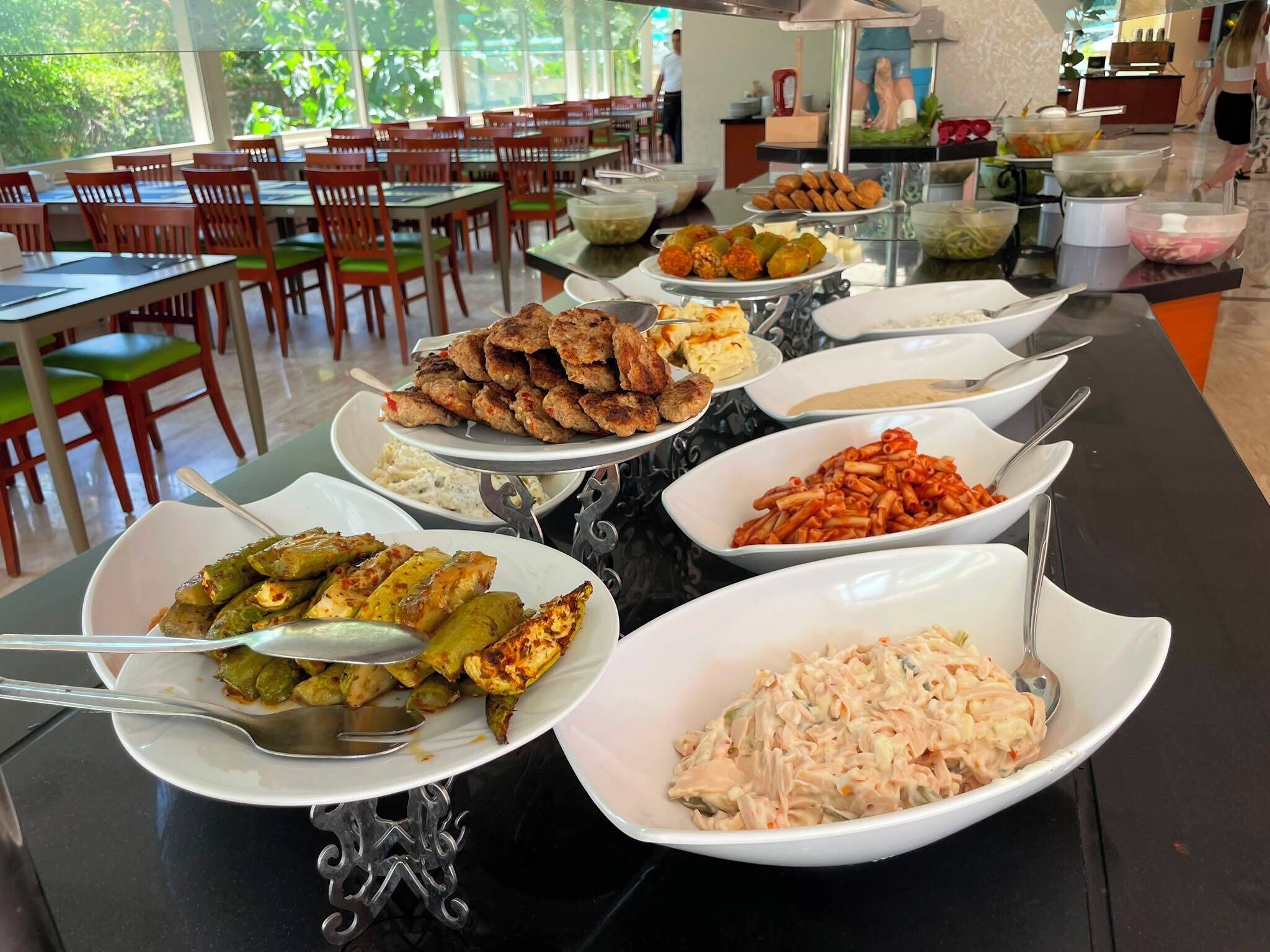 A buffet with various dishes including meatballs, pasta, and vegetables.