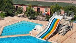 Una piscina con un tobogán colorido y un puesto de socorristas.