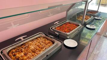 Un bufé con diversas opciones de comida, incluyendo un plato con pimientos rojos y un cazuela con queso.