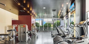 A gym with cardio machines, weight equipment, and large windows offering a view of the outdoors. - Grand 1BR · Intracoastal & Sunset View · Resort (Hallandale Beach)