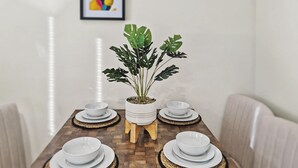 A dining table with four white bowls and plates, a potted plant, and a framed picture on the wall. - Stylish 2BR Solihull Stay | Near NEC | Parking | Garden (Solihull)